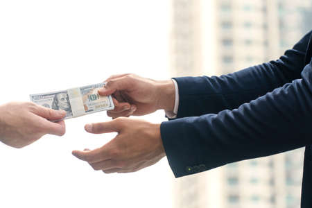 Payment financial concept. Hand of businessman holding dollar banknotes pay-off for bribe or giving...