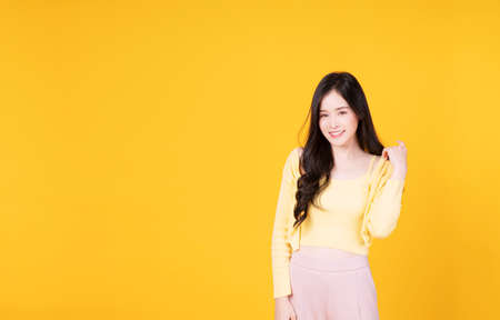 Confident charming Asian young woman wear hipster style standing over isolated yellow background. Cheerful student or businesswoman smart success while looking at camera.の写真素材