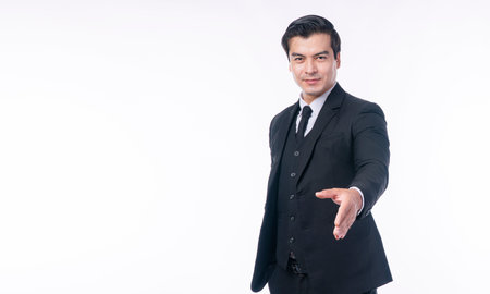 Confident friendly handsome smart positive young businessman wear suit holding handshake after deal work success while standing over isolated white background. Businesspeople successful concept.の写真素材