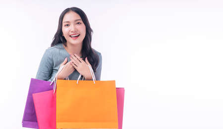 Enjoyment excited asian woman carry shopping bags standing on white background. Trendy happy shopper...