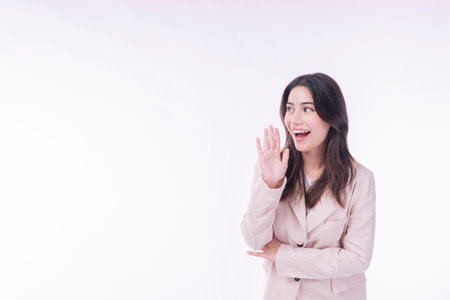 Excited cheerful young girl yelling advertise holding hand beside mouth standing over isolated white...