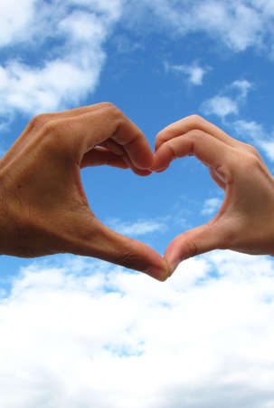Lover hands forming in a heart over the sky