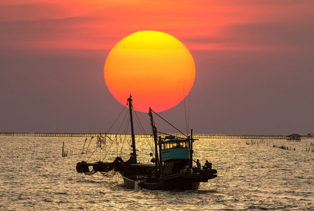 fishermen on the boat in  the sea on sunset time at Thailandの写真素材