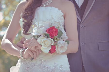 Bride and groom holding hands and a bouquet of beautiful flowers as symbols on the wedding.の写真素材