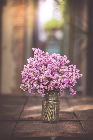 A bouquet of purple flowers in a glass vase on a wooden floor boards of old vintage. The home decorの写真素材