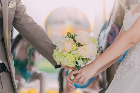 Bride and groom holding hands and a bouquet of flowers as a token of love and marriage.の写真素材