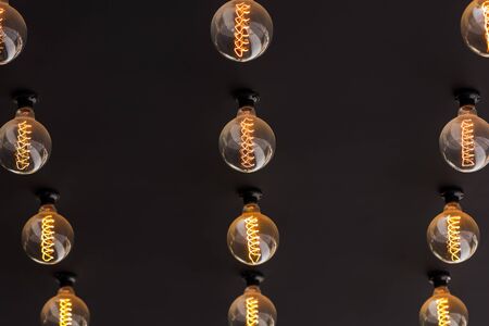 Old-fashioned light bulb turned on. On the dark surface, the concept of creativity in decorative...