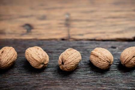 still life with Walnut kernels and whole walnuts on rustic old wooden table