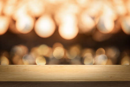 Gold color bright lights bokeh background of wooden table in front of lights abstract blurred and...