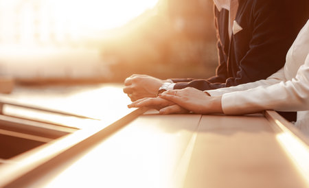 Hands of a young couple on a table by the river in the evening, the moment when the sunset lights up.の写真素材