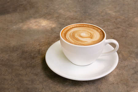 Hot coffee cappuccino latte art spiral shape in ceramic cup on concrete table backgroundの写真素材