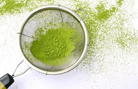 Traditional organic Japanese green tea powder in tea strainer prepare match latte top view on white...