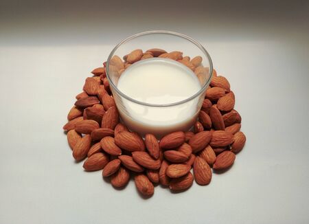 glass with almond milk and almonds on white backgroundの写真素材