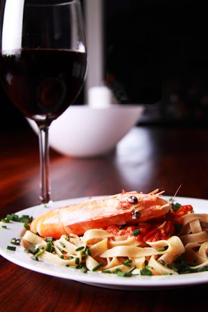 Shrimp pasta on a white plate served on a mahoney tableの写真素材