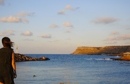 Sunset with a girl looking at the greek mediterranean seaの写真素材