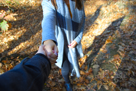 A beautiful woman is taking a helping hand to climb a hill in the forest of Duisburg in Germanyの写真素材
