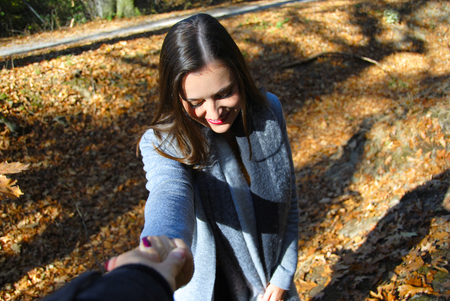 A beautiful woman is taking a helping hand to climb a hill in the forest of Duisburg in Germanyの写真素材