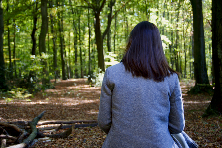 A beautiful woman sitting on a trunk in the forest of Duisburg, Germanyの写真素材