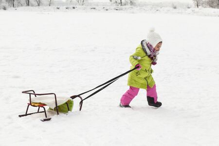 Happy child girl in winter clothes playing with snow. winter funの写真素材