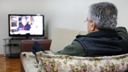 Senior man watching TV show while sitting on sofa in his living room