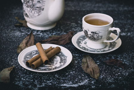 A cup of tea with some snack and old leafの写真素材