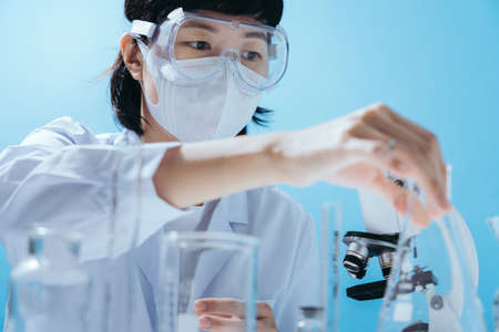 Close up smart young asian female scientist in lab coat with Medical face mask. Inspection on...