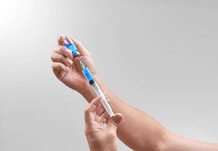 Doctor hand extracting medical drug. Bright grey background. Medical concept for health care,...