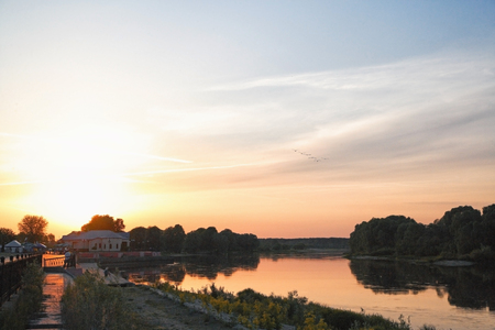 summer landscape pink and orange sunset over the tranquil river and trees on the shoreの写真素材