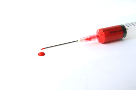 Red liquid in the syringe and drop on white ground.の写真素材