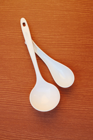 two white plastic  spoon on the wooden backgroundの写真素材
