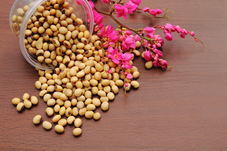 soy beans are pouring on the wooden floor and decorate with pink flower