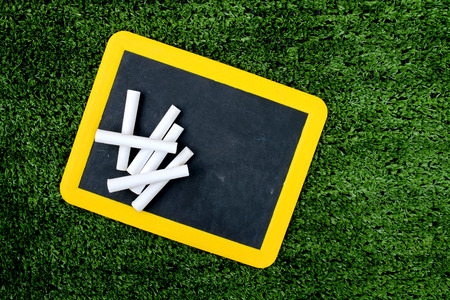 used plastic blackboard and pile of white chalk on turfの写真素材
