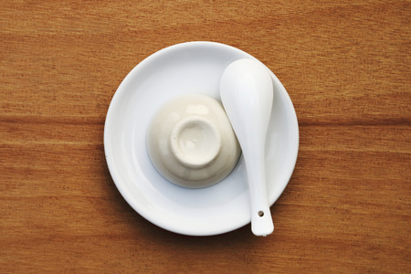 white table set which have plate spoon and bowl on wooden backgroundの写真素材