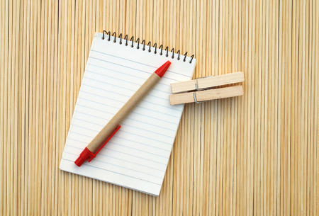 pen and notepad with wooden clips are on bamboo mattの写真素材