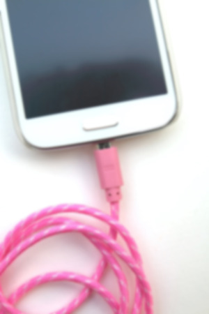 pink cable stick with mobile telephone in soft focus