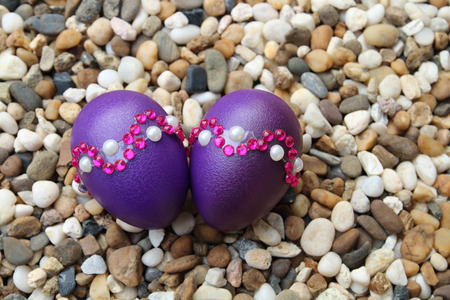 purple eggs are decoration with sticker putting on pebbleの写真素材
