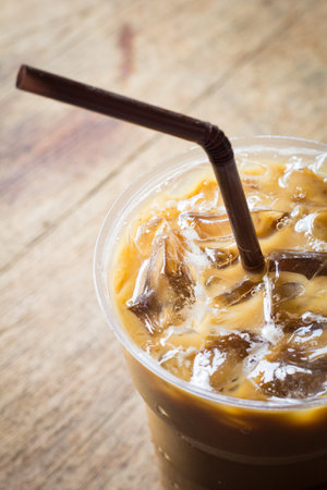 Iced coffee in plastic cup on wooden table. Close up.の写真素材