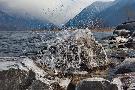 The beating waves on the rocks. Russia. mountain Altai. Early spring in the South of the lake Teletskoye.の写真素材