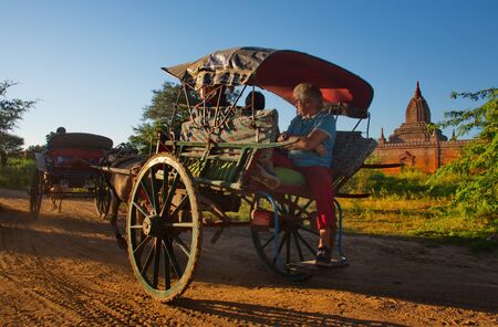 BAGAN. MYANMAR. November 25, 2016. A horse-drawn cart with tourists on a dusty road in the background light hurries to the amazing Buddhist temples of Bagan to see the blazing sunset.のeditorial素材
