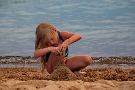 BALYKCHI. KIRGHIZIA. August 13, 2019. A little girl is trying to build a sand castle on the shore of lake Issyk-Kul.のeditorial素材