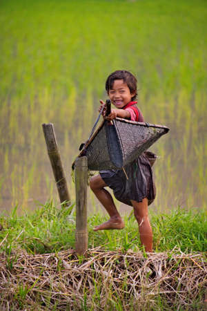 Gauhati. Eastern India. February 11, 2016. Village girls relax after a successful fishing trip in a rice field. Fishing with wicker nets for small fish is a traditional activity for children from Indian villagesのeditorial素材