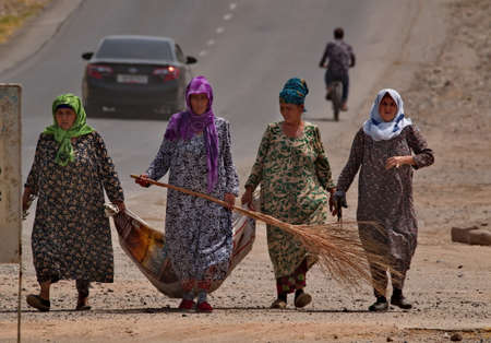 Nurek. Tajikistan. August 07, 2019. Women in national clothing manually sweep and collect garbage on the streets of the city. Traditionally, only women do this here.のeditorial素材