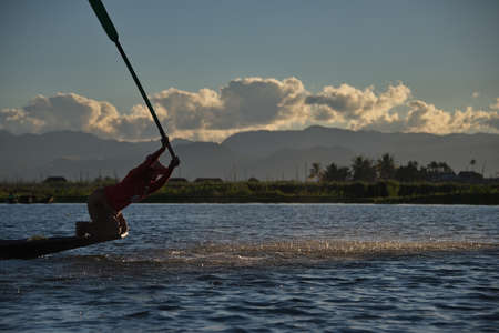 The Inle Lake. Myanmar. 11/27/2016. At sunset the fishermen are fishing in an unusual way - standing on the edge of the boat and driving the paddle leg, cast net and drive the fish strikes the water.のeditorial素材