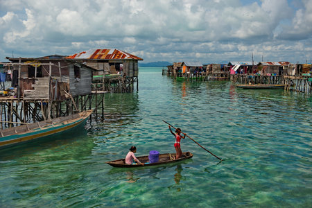 Semporna. Malaysia. November 30, 2018. Young residents of the village of sea Gypsies joyfully meet the boat with tourists. From a young age, children masterfully master the art of managing light boatsのeditorial素材