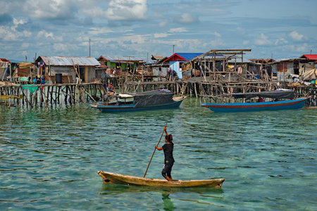 Semporna. Malaysia. November 30, 2018. Young residents of the village of sea Gypsies joyfully meet the boat with tourists. From a young age, children masterfully master the art of managing light boatsのeditorial素材