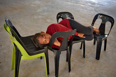 Semporna. Malaysia. December 02, 2018. A woman sleeps sweetly on plastic chairs after cleaning the...