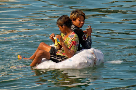 Semporna. Malaysia. November 28, 2018. Children of sea gypsies swim in the sea on polypropylene bags filled with empty plastic bottles. The cost of such watercraft is almost free.のeditorial素材