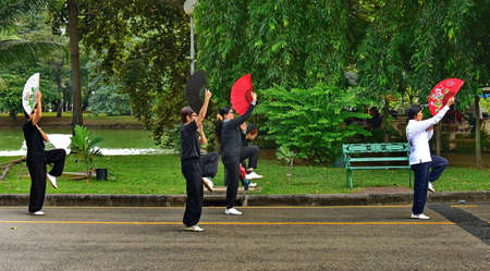 Bangkok. Thailand. December 02, 2016. In the early morning in the city's Lumpini Park, a group of women perform traditional Tai Chi wellness exercises with a fan.のeditorial素材