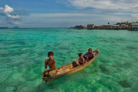 Semporna. Malaysia. December 01, 2018. The children of the sea gypsy village artfully swim in boats between the huts on stilts. From a young age, children master the art of controlling boats at sea.のeditorial素材