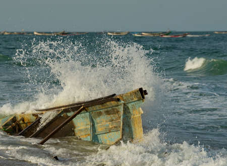 West Africa. Mauritania. Sea water splashes from the impact of coastal waves on the side of the remains of a broken fishing boat washed up on the Atlantic Ocean near the city of Nouakchott.の写真素材